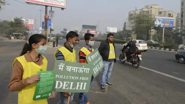 Civil defence volunteers stand on Delhi roads holding placards on the Day-5 of implementation of state government’s odd even formula in the national capital on January 5, 2016. (Photo: IANS)