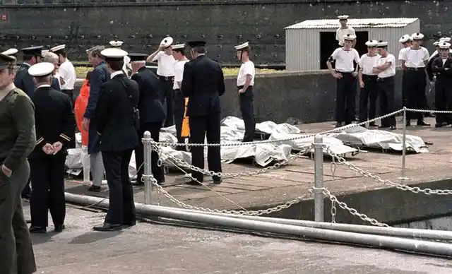 Officers, Irish sailors, and rescue workers look on as the 329 victims of the Air India jet are lined up on the docks in Cork, Ireland on 24 June 1985. (Photo: Reuters) 