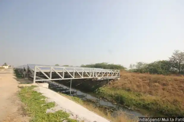 As the midday sun beats down relentlessly, solar panels fixed at an angle atop a 750 m long length of canal in Chandrasan village, Mehsana district, work quietly to produce power while saving evaporation of water that runs beneath. (Image courtesy: IndiaSpend/Mukta Patil)
