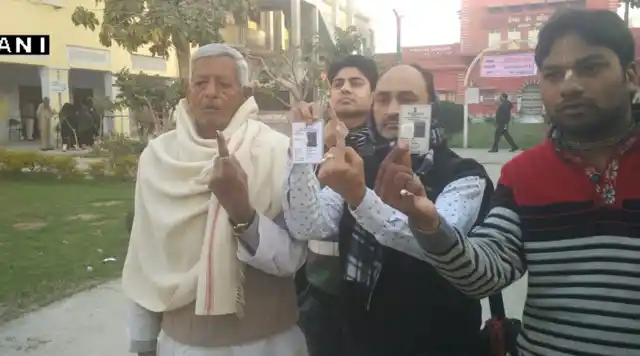 People show their inked fingers and voter IDs after casting their votes in Baghpat. (Photo: ANI) 