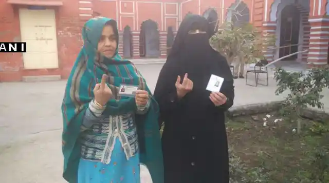 Two women show their inked fingers after casting their votes in Baghpat. (Photo: ANI)