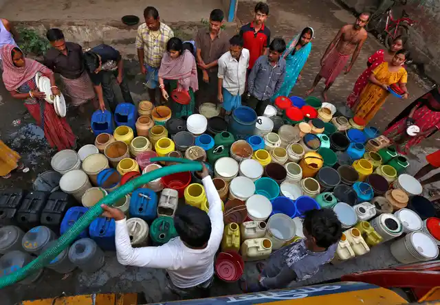 Residents wait as they get their containers filled with drinking water from a municipal tanker at a slum in Kolkata. (Photo: Reuters)