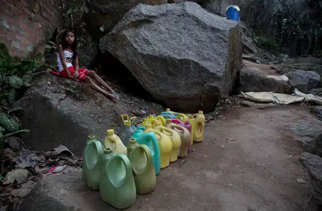 A girl waits for the arrival of water supply at a public tap, next to plastic cans lined up by others for collecting drinking water in a hilly area on the eve of World Water Day in Guwahati. (Photo: AP)