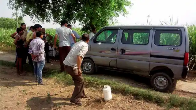 Villagers look on as police investigate near the vehicle, Maruti Suzuki Eeco, in which seven members of family along with a driver were travelling while being attacked. (Photo: PTI)