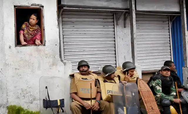 Security personnel sit as a woman looks out of a window in Darjeeling on Sunday. (Photo: PTI)