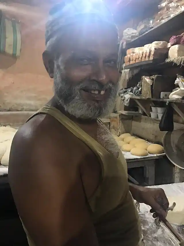 A worker at the bakery smiles as he starts his chores.