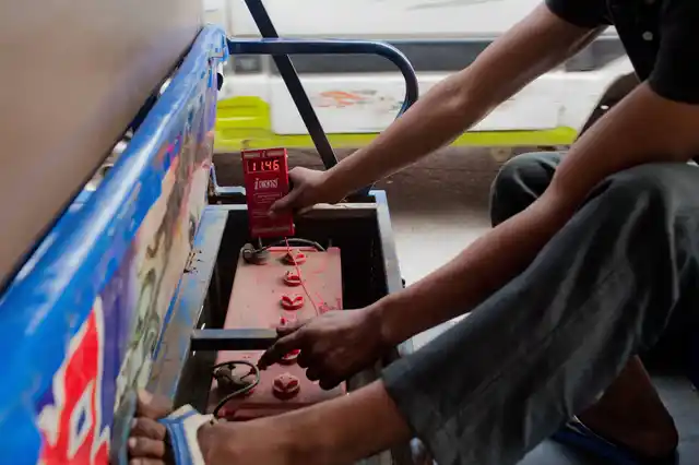 A mechanic checks the battery-pack of an electric rickshaw. 
