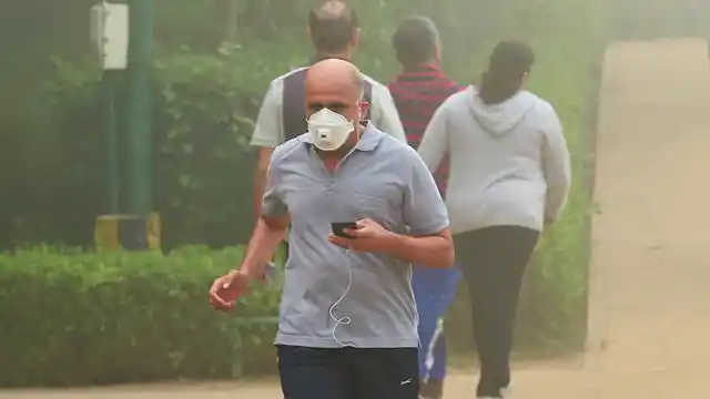 A man wearing an anti-pollution mask jogs through smog at Lodhi Garden in New Delhi on Tuesday, 7 November.