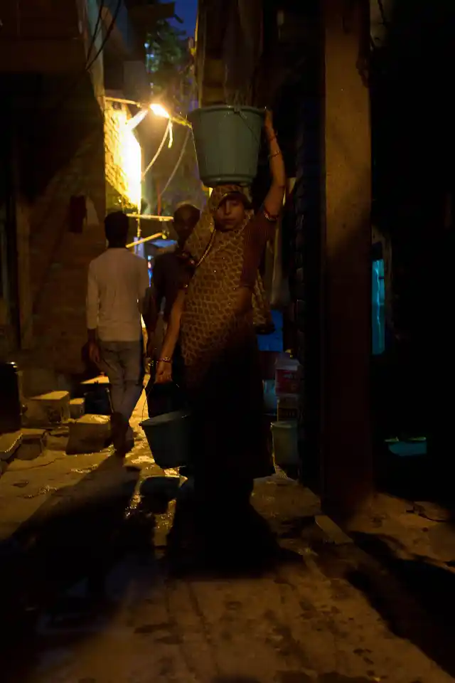 A woman carrying a bucket of water from a nearby tap in Kabir Nagar basti, north Delhi. 