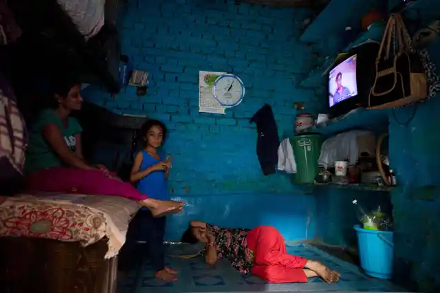 A family watching television inside their one room house in Chandrawal basti, north Delhi.