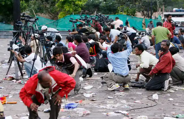 Journalists duck from getting hurt while covering the attacks outside the Taj Mahal Hotel