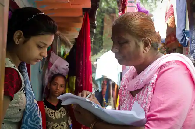 Mehender Kaur giving a notice circular to a house in Sanjay Basti over non-payment of dues. 
