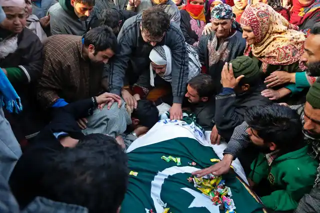 Militant Basit Rasool Dar’s brother cries over his body during his funeral procession in Marhama in Kashmir December 2016.