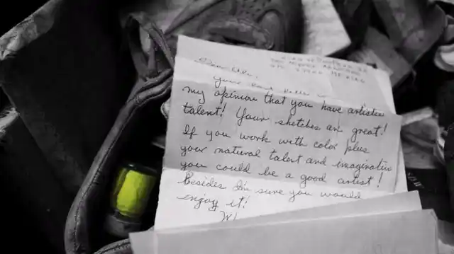 A letter addressed to Ali, appreciating his art, lies next to a crate full of old paint.