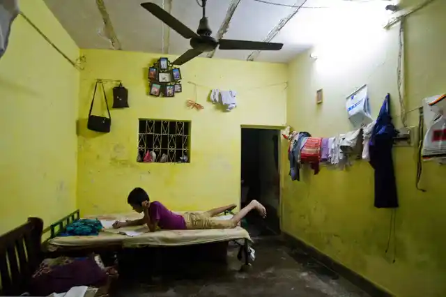 A kid studies under a tube light inside his house in Chandrawal basti, north Delhi.