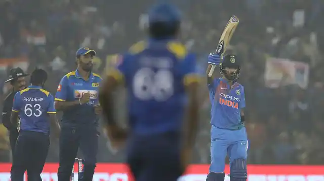 KL Rahul raises his bat to celebrate his half century.