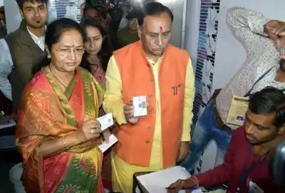 Rajkot: Gujarat Chief Minister Vijay Rupani and his wife Anjali Rupani at a polling booth during the first phase of Gujarat election in Rajkot on Dec 9, 2017. (Photo: IANS)