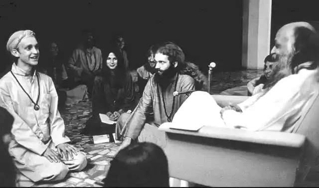A photo of Osho with his disciples in <i>darshan</i> at Poona in 1977.