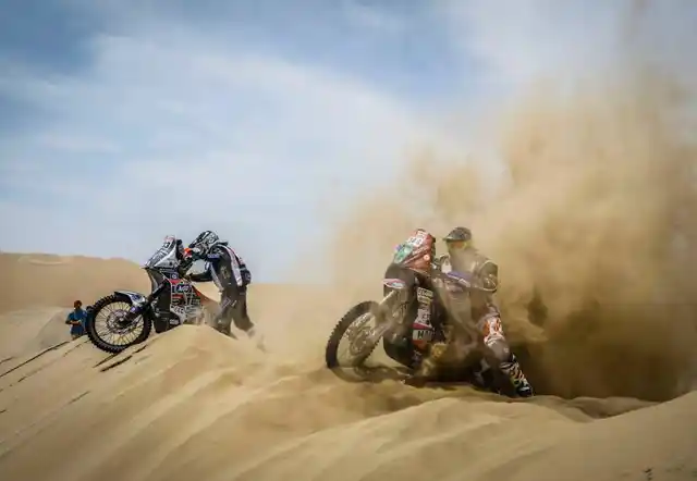 Two bike racers struggle to keep themselves balanced in the sand.