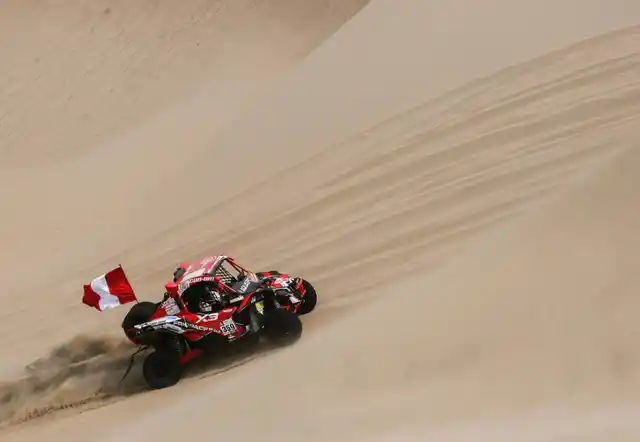 An SxS class vehicle blows some sand.