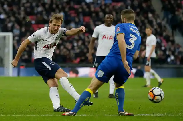 Tottenham’s Harry Kane, left, shoots past Wimbledon’s Jonathan Meades.