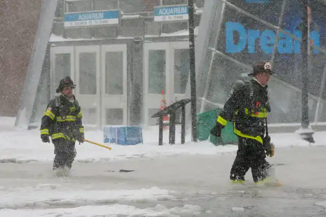 Boston firefighters wade through a street flooded from tidal surge during Storm Grayson in Boston, Massachusetts.