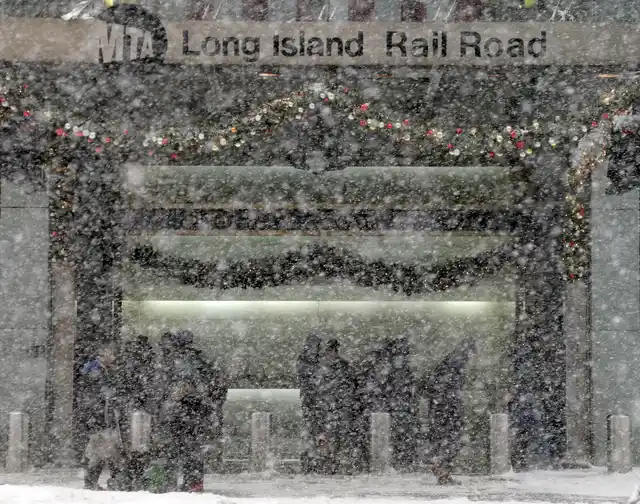 Pedestrians at the entrance of the Long Island Railroad are obscured by snow in New York.