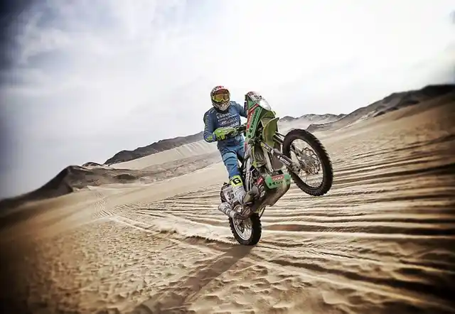 A biker pops a wheelie during the third stage.