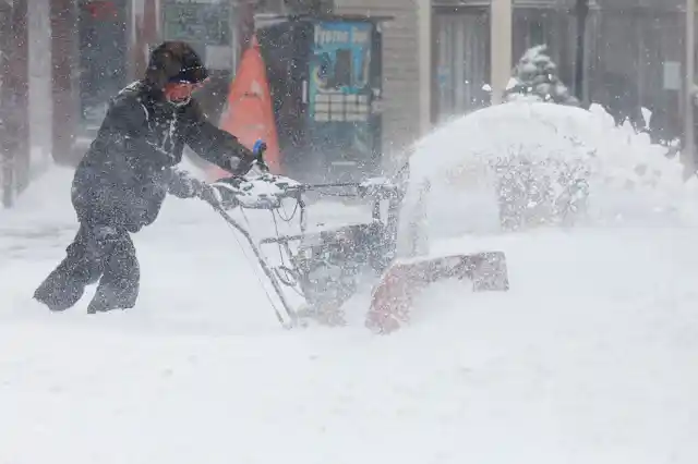 A man uses a snowblower to clear snow from a street during a snowstorm in Port Washington, New York.