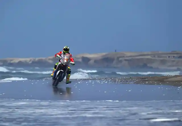 A biker tackles a wet patch.