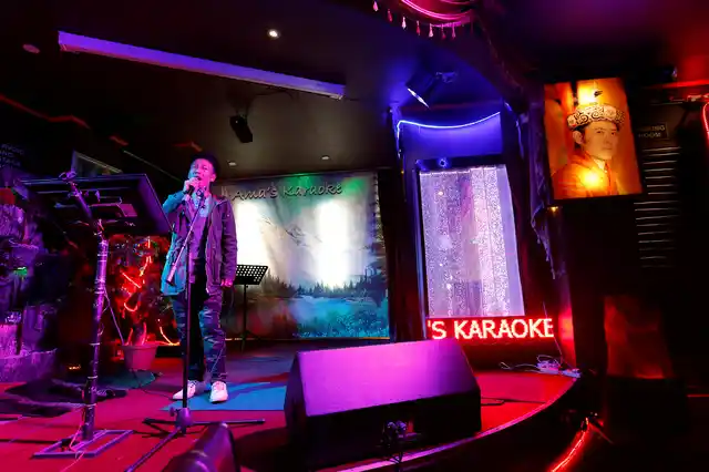 A man sings in a Karaoke bar beside a portrait of King Jigme Khesar Namgyel Wangchuck in the capital city of Thimphu, Bhutan, 16 December 2017. 