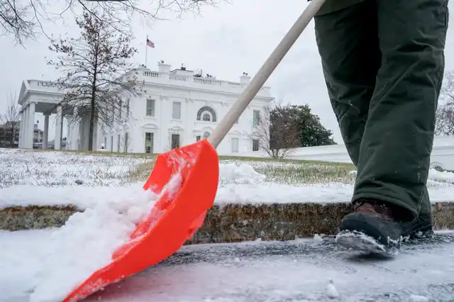 A National Park Service worker clears snow on the North side of the White House. 