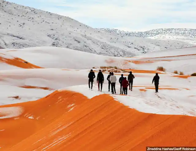 People walking on snow-capped mountains in Sahara.