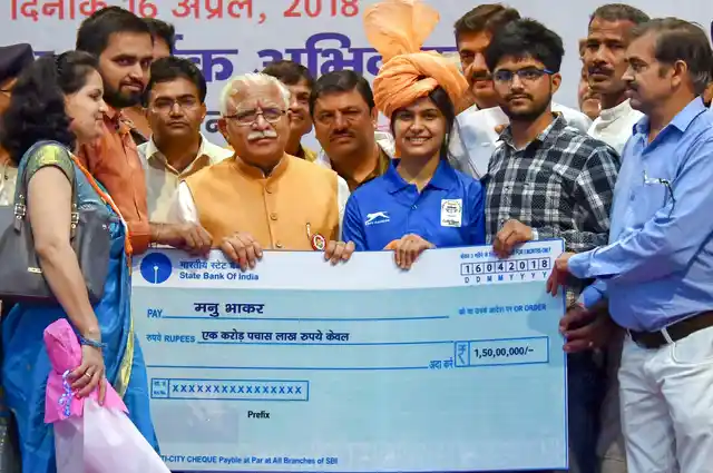 Haryana Chief Minister Manohar Lal Khattar presents a cheque worth Rs 1.5 crore to Commonwealth gold medal winner shooter Manu Bhaker, in Jhajjar on 16 April.