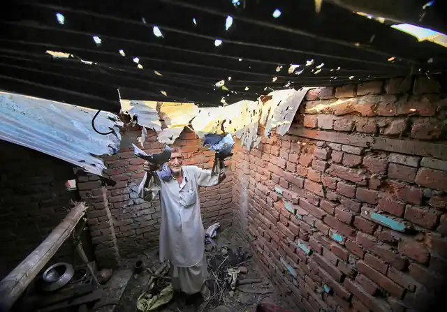 A villager shows a roof, claimed to be damaged after firing from the Pakistani side.
