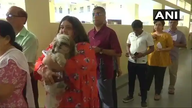 A woman waits in queue at polling booth number 172 in BTM constituency, with her dog in tow.