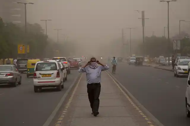A man wraps a scarf around his nose as a dust storm envelops the city in New Delhi, Wednesday, May 2.