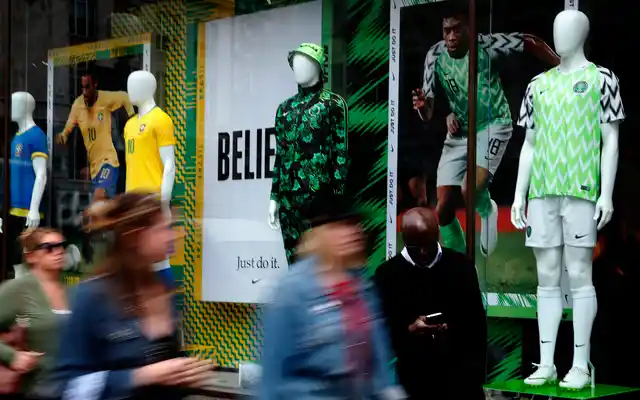People walk by Nigerian and Brazil national soccer team jerseys which are on display at a shop in London. 