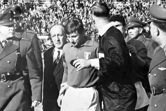In this file photo from 2 June 1962, Italian forward Giorgio Ferrini, centre, is sent off by British referee Ken Aston, back to camera, after an incident during the first half of the World Cup match between Italy and Chile in Santiago, Chile. Ferrini refused to leave the field after being ordered off by the referee and was removed by police officers. 