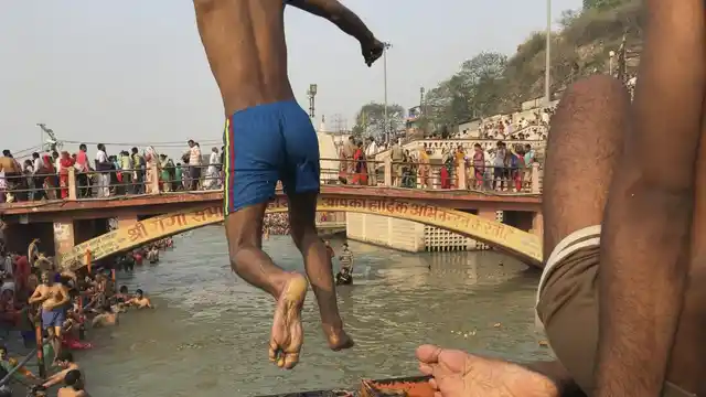 Young men jumping into the fast flowing waters at Har Ki Pauri, each trying to jump higher, and more times, than the rest.