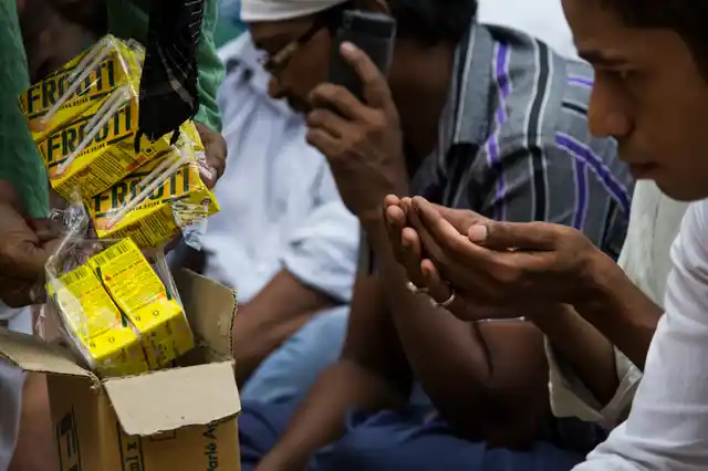 Devotees sit in a queue to receive Iftar food from the Khuddams (servers).