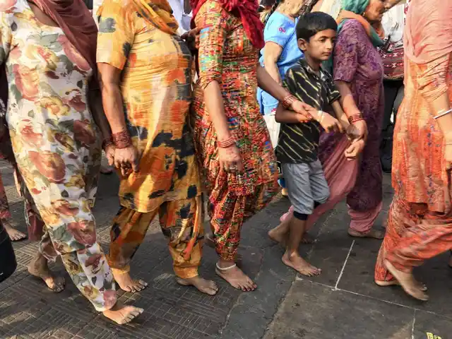 Women and children walk in a file, holding hands so that no one gets lost in the rush of activity at the ghats.