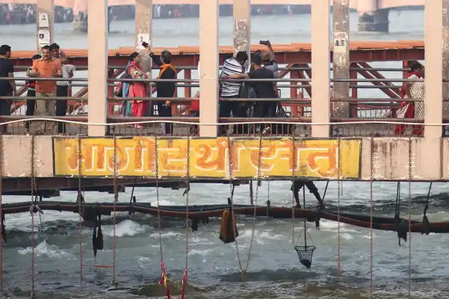 While pilgrims with smart phones take selfies on the bridge, one man under the bridge dangles a catch net into the fast flowing waters to scrape off offerings from the water. These will be then re-packaged and re-sold in the market.
