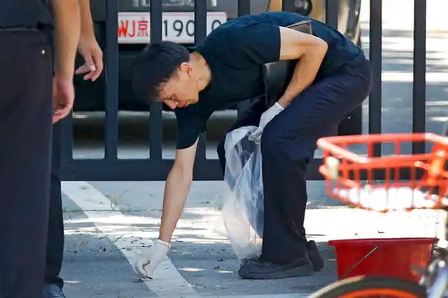 A crime scene investigator collects fragments from the spot of the blast outside the US embassy in Beijing