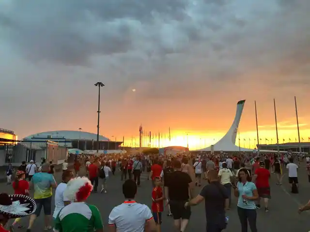 The fiery glow of the setting sun behind the Olympic torch next to the Fisht Stadium welcoming the Portugal and Spain fans.