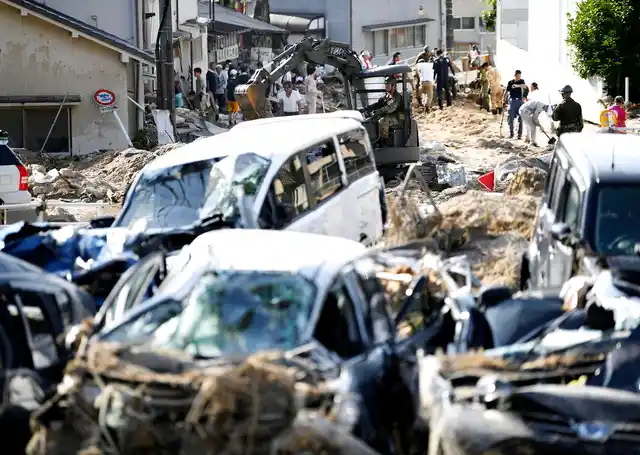 Cars are trapped in mud as residents clean up after days of heavy rain in Hiroshima city, southwestern Japan, on Tuesday, 10 July.