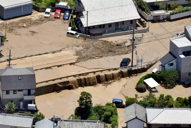Mud waters cover the streets after the Enoki River running through the town overflowed, in Fuchu, Hiroshima prefecture, southwestern Japan, on Tuesday, 10 July. 