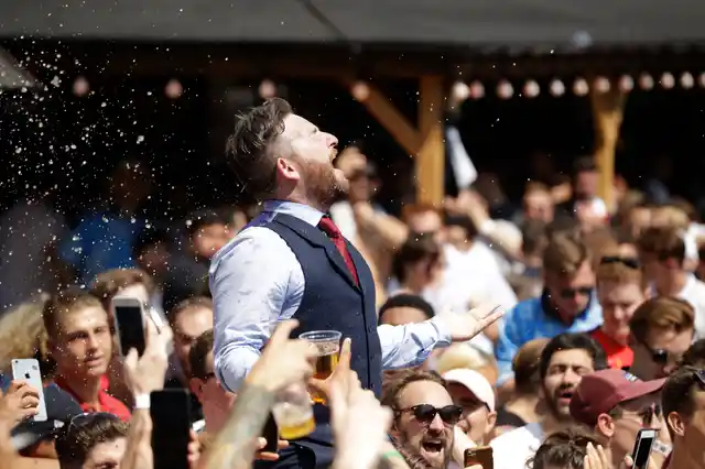 An England soccer fan dressed in a waistcoat to mimic England manager Gareth Southgate, is lifted up as fans gather to watch a live broadcast on a big screen of the quarterfinal match between England and Sweden at the 2018 soccer World Cup, in Flat Iron Square, south London, Saturday, July 7, 2018. 