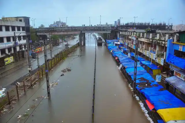 A suburban train wades through water-clogged railway tracks after heavy rainfall, in Nalasopara station on Tuesday, 10 July.