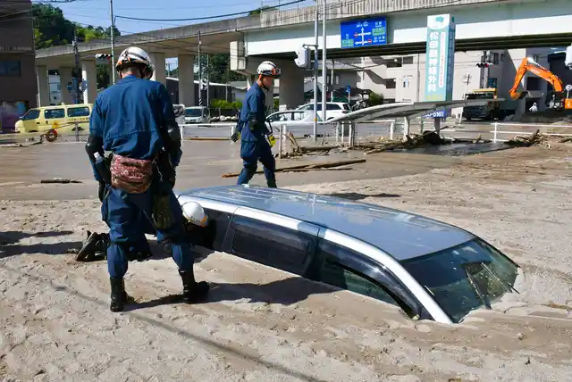 A police officer looks into a car buried in mud during a search operation in the aftermath of heavy rains in Kure, Hiroshima prefecture, southwestern Japan, on Wednesday, 11 July.